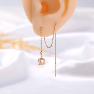 Macro detail of crown tassel earrings with shiny zircons on 18k gold plating