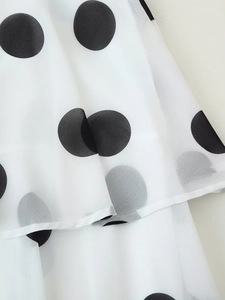 Detailaufnahme des weißen Stufenrocks aus Chiffon mit klassischem schwarzem Punktmuster