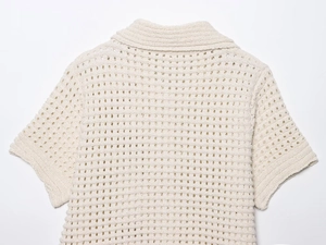 Close-up of cream knit short sleeve top with hollow crochet and fringe texture