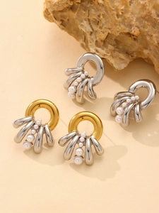 Macro detail of octopus-inspired shell pearl earrings with layered gold and silver fan metal