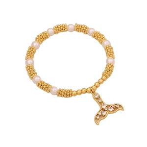 Beaded gold and pearl bracelet with a sparkling fishtail charm on a white background
