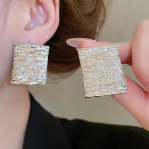 Detailed view of silver metallic geometric earrings featuring unique bark-like textured surface