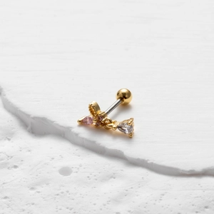 Macro detail of gold double-headed stud earring with pink zircon butterfly and steel post