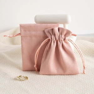 Pink microfiber drawstring pouch for jewelry storage on minimalist white display stand
