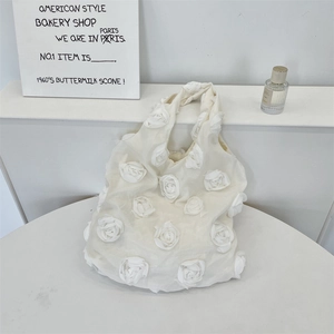 Detail shot of cream white tote bag featuring 3D dimensional rose petals on fabric