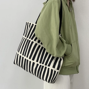 Detail view of large capacity black and white striped canvas tote bag on female model