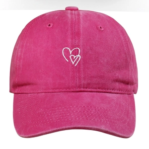 Dettaglio del cappellino in cotone lavato rosa con ricamo di cuori bianchi sul fronte