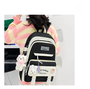 Close-up of black and white student backpack with cute plush bear and rabbit pendants