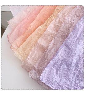 Detail of colorful wrinkled tissue paper showing soft pink, apricot, and lilac textures