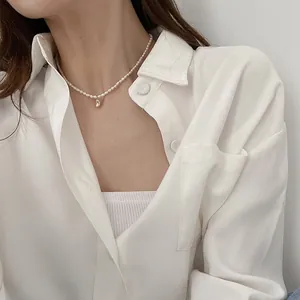 Macro detail of natural freshwater pearl necklace with a minimalist gold bean pendant