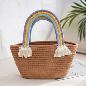Detail of woven straw handbag featuring a colorful rainbow handle and white cotton tassels