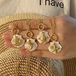 Detail of four golden ocean shell pendants featuring fish, dolphin, turtle and starfish