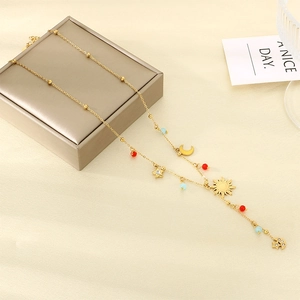 Detail of gold celestial necklace with sun and moon charms on a gold jewelry box