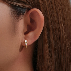 Macro shot of S925 silver hoop earring with teardrop and baguette cut sparkling zircons
