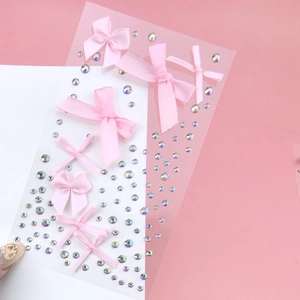 Detail of pink ribbon bow stickers and shimmering rhinestones on a clear adhesive sheet