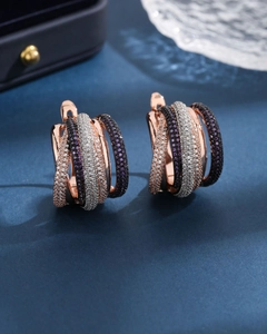Rose gold tiered hoop earrings with purple and white pavé zircon stones on blue background