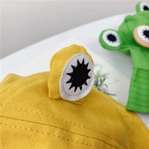 Detail of cute frog eye embroidery on yellow and green canvas bucket hats for kids