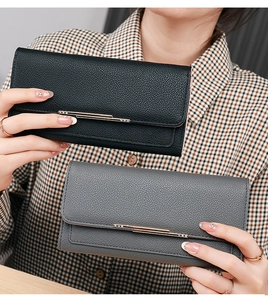 Detail of lychee pattern leather wallets in black and grey with gold metal bars