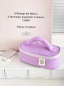 Pastel purple pleated nylon handbag with a smileday patch on a minimalist white desk