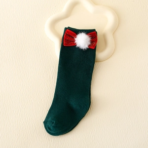 Detail of dark green knit Christmas socks with a red bow and white pompom accent