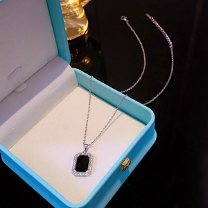 Detail of silver chain with black rectangular pendant and crystals on blue box