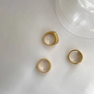 Macro shot of three minimalist gold layered rings with twisted rope and polished textures