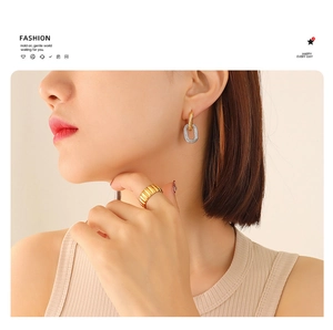 Detail of two-tone interlocking oval earrings and textured gold band ring on model