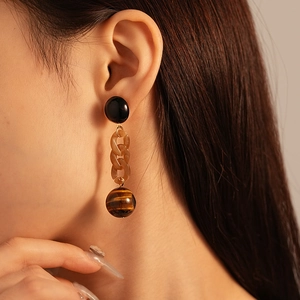 Close-up of vintage resin chain earrings with tiger eye stone bead on female model