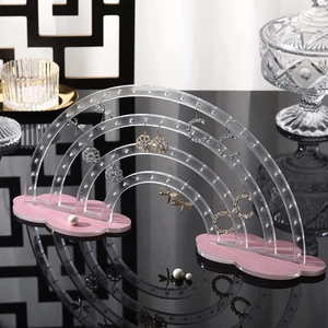 Rainbow acrylic earring display stand with a pink cloud base on a mirrored surface