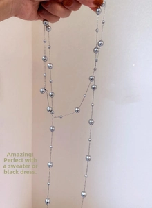 Detailed close-up of a long gray pearl necklace with a thin elegant chain design