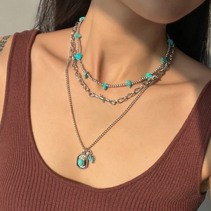 Close-up of layered bohemian turquoise necklace featuring cactus charm and silver beads