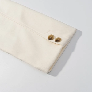 Detail shot of off-white wool jacket cuffs with brown amber buttons and thick texture