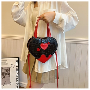 Close-up of heart-shaped handbag with crocodile texture and red contrast detailing