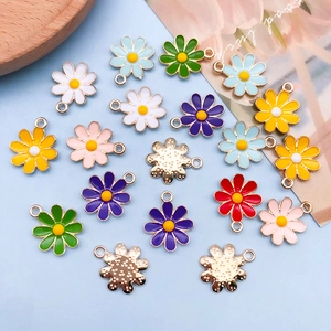 Colorful enamel daisy flower charms in various colors on light blue background