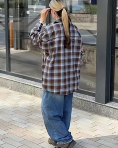 Vista esterna di una camicia a quadri rilassata abbinata a jeans larghi blu da donna