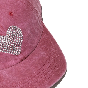 Detailed macro view of sparkling rhinestone heart on pink corduroy baseball cap