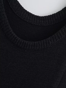 Détail de la robe en tricot noir montrant le col rond et la texture de la maille