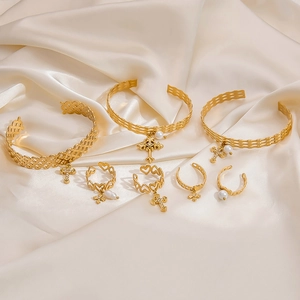 Detailed close-up of golden cross and pearl open bracelet on elegant satin background