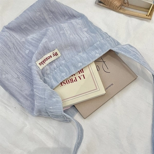 Dettaglio della borsa tote in velluto azzurro con motivi a cuore e etichetta tessuta