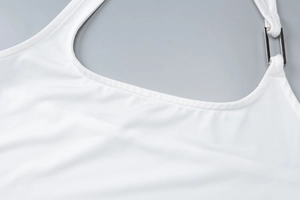 Détail d'un crop top blanc avec tissu lisse et une boucle métallique sur la bretelle