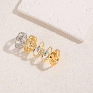 Macro shot of four gold and silver star moon evil eye zircon rings on stone surface