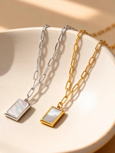 Gros plan de pendentifs rectangulaires en nacre sur chaînes trombones or et argent