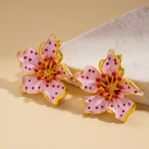 Macro shot of floral stud earrings with pink enamel coating and red stamen details