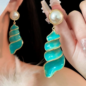 Detail of vintage gold earrings with white pearl and turquoise shell-shaped enamel drops