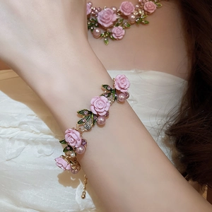 Detail of flower bracelet with pink roses green leaves and purple beads on gold chain