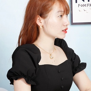 Close-up of golden crescent moon necklace and earrings set worn by a model