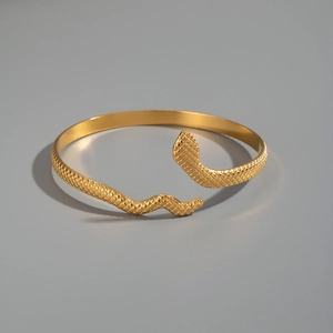 Detailed close-up of golden snake-shaped bracelet with intricate scale pattern engravings