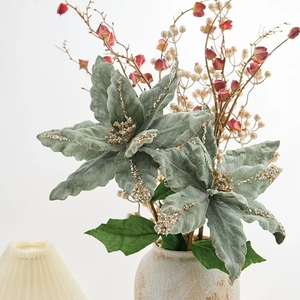 Fleur de Noël artificielle en velours vert avec paillettes dorées dans un vase en céramique