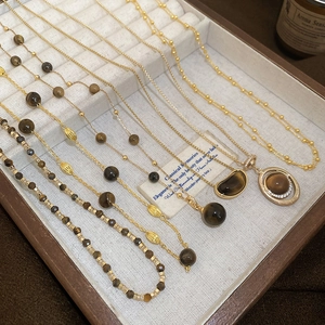 Flat lay of tiger eye pendant necklaces and gold beaded chains on jewelry display tray