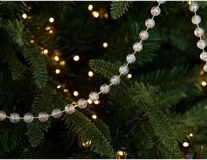 Iridescent clear bead garland hanging on a Christmas tree with warm festive lighting